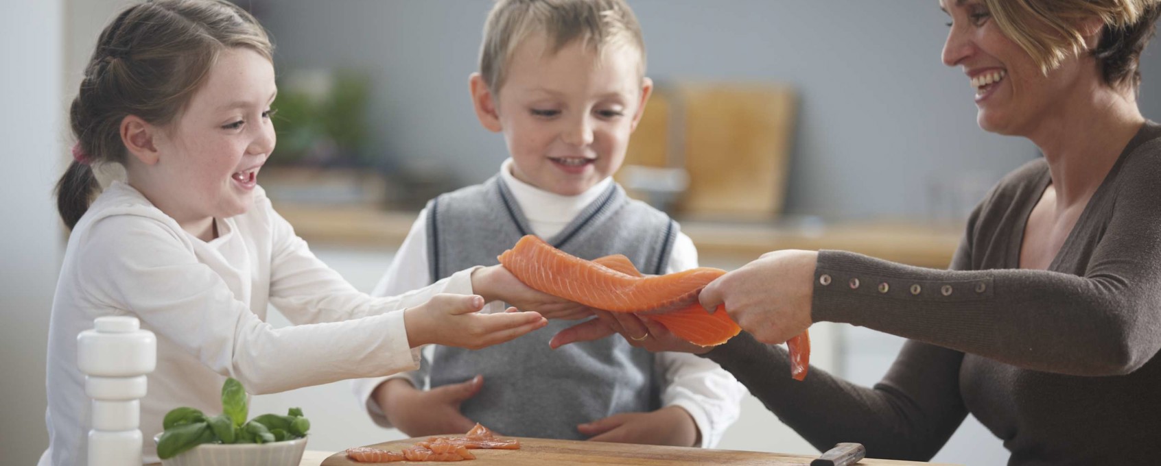 Barn på kjøkkenet med mor prøver laks